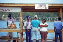 BAHAMAS, New Providence Island, Nassau, Potters Cay, people chatting by stall, BAH196JPL