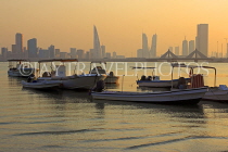 BAHRAIN, Muharraq, coastal fishing village area, boats, and Manama skyline, dusk, BHR2487JPL