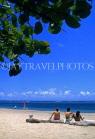 DOMINICAN REPUBLIC, North Coast, beach at Playa Dorada, holidaymakers seated on tree trunk, DR122JPL