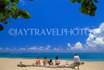 DOMINICAN REPUBLIC, North Coast, beach at Playa Dorada, holidaymakers seated on tree trunk, DR426JPL
