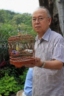 HONG KONG, Kowloon, Mong Kok, Yuen Po Street Bird Garden, man with songbird in cage, HK936JPL