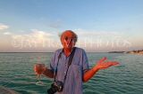 JAMAICA, Montego Bay, man (tourist) enjoying his wine, by the sea at sunset, JM320JPL