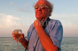 JAMAICA, Montego Bay, man (tourist) enjoying his wine, by the sea at sunset, JM321JPL