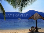 MALAYSIA, Pangkor Laut Island, seascape and tourist under thatched sunshade, MSA295JPL
