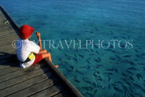 MALDIVE ISLANDS, boy feeding fish from pier, MAL13JPL