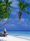 MALDIVE ISLANDS, holidaymaker on beach by leaning coconut tree, MAL124JPL