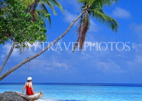 MALDIVE ISLANDS, holidaymaker on beach by leaning coconut tree, MAL731JPL