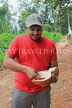 SRI LANKA, countryside, man eating a king coconut (Thambili) kernel, SLK4567JPL