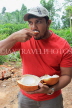 SRI LANKA, countryside, man eating a king coconut (Thambili) kernel, SLK4568JPL