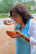 SRI LANKA, countryside, woman eating a king coconut (Thambili) kernel, SLK4569JPL