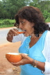 SRI LANKA, countryside, woman eating a king coconut (Thambili) kernel, SLK4570JPL