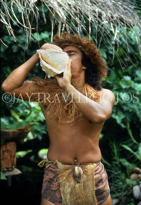 COOK ISLANDS, Rarotonga, Cultural Village, Maori man blowing conch shell, CI922JPL